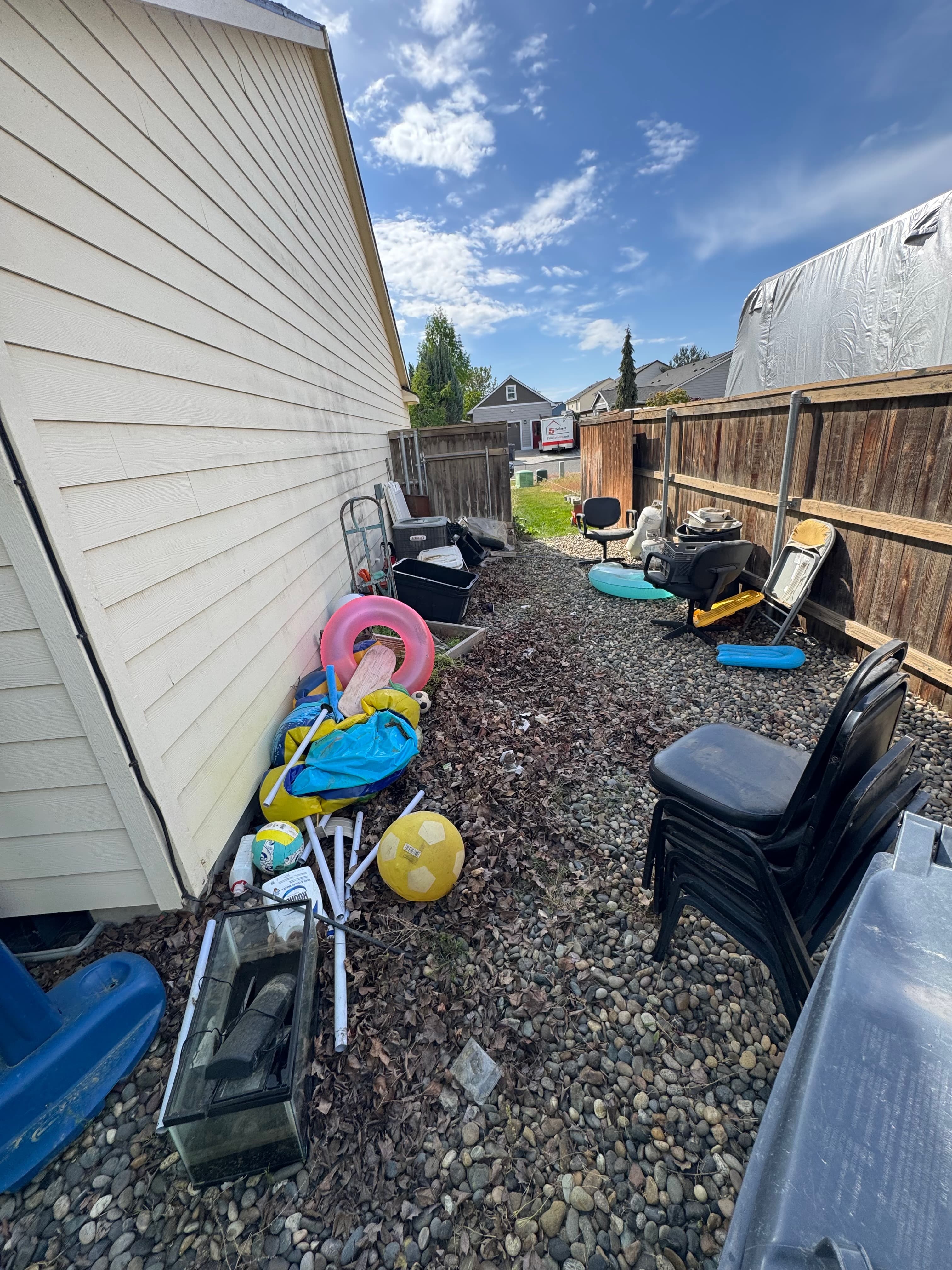 Wide view of cluttered side yard before outdoor junk and debris removal