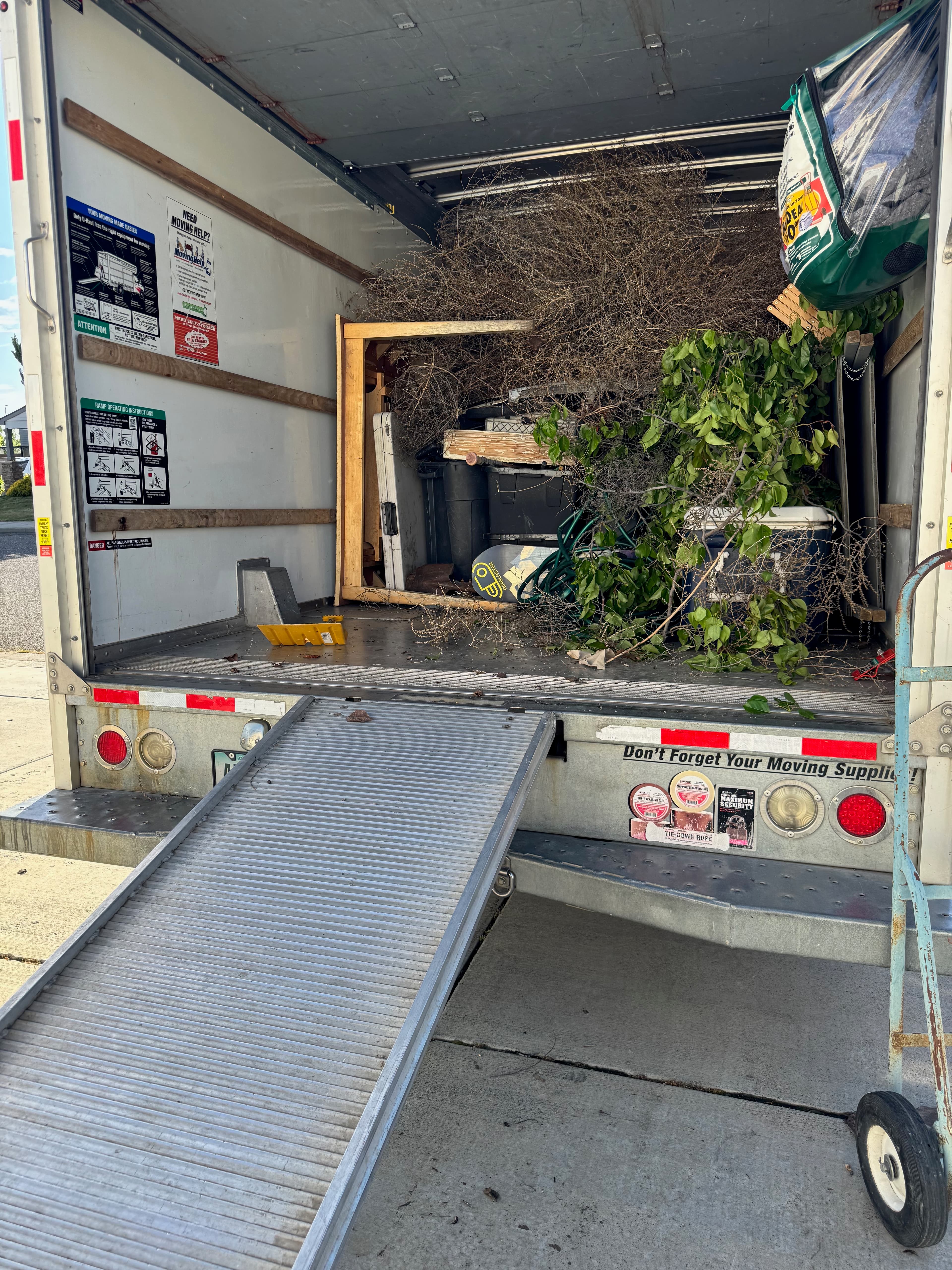 Moving truck loaded with yard debris, branches, bins, and bulky junk
